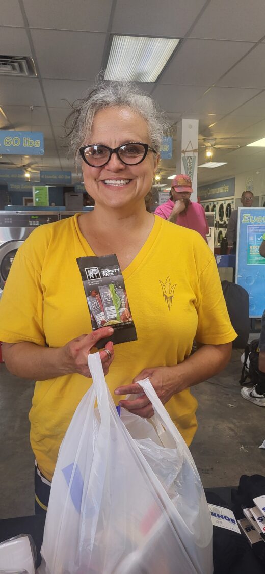 An individual receives LMNT electrolyte packets during an Arizona heat relief outreach with Arizona’s Family to the Homeless at Social Spin.